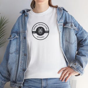 May include: White t-shirt featuring a black and white circular logo that reads "Animal Revolution Apparel" with a wolf's head inside the circle. The logo also states "Est. 2025".