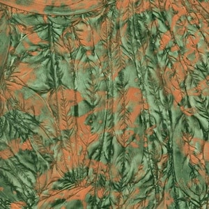 May include: Abstract textile with a pattern of stylized feathers in shades of green and orange. The design features vertical lines and overlapping feather shapes, creating a textured appearance. The color palette is earthy and organic.
