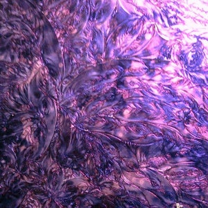 May include: Abstract close-up of a textured surface with a floral pattern. The design features a blend of dark purple and lighter lavender hues, creating a sense of depth and dimension. The intricate details suggest a fabric or decorative element.