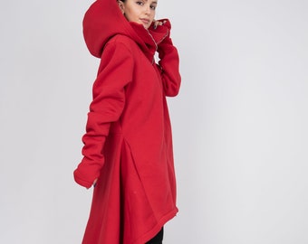 May include: A long, flowing red hooded coat with a unique asymmetrical hemline. The coat features long sleeves and a high collar, paired with black pants and high-heeled boots. The design is modern and stylish.