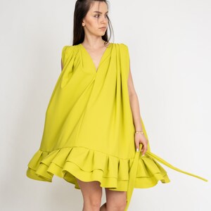Peut inclure: Une robe sans manches vert citron avec un ourlet &agrave; volants et une ceinture &agrave; nouer &agrave; la taille. La robe est fluide et a une coupe ample.