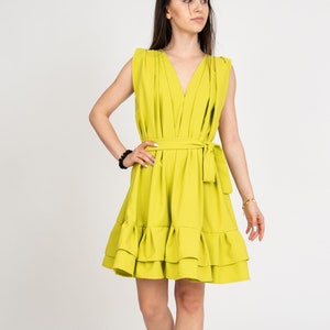 Peut inclure: Une robe jaune vif sans manches avec un d&eacute;collet&eacute; en V, une ceinture &agrave; nouer &agrave; la taille et un ourlet &agrave; volants.