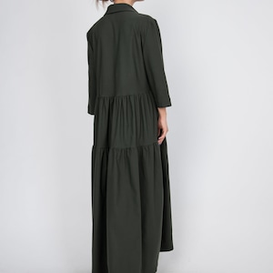 May include: A long, dark green tiered dress with a collared neckline and three-quarter sleeves.