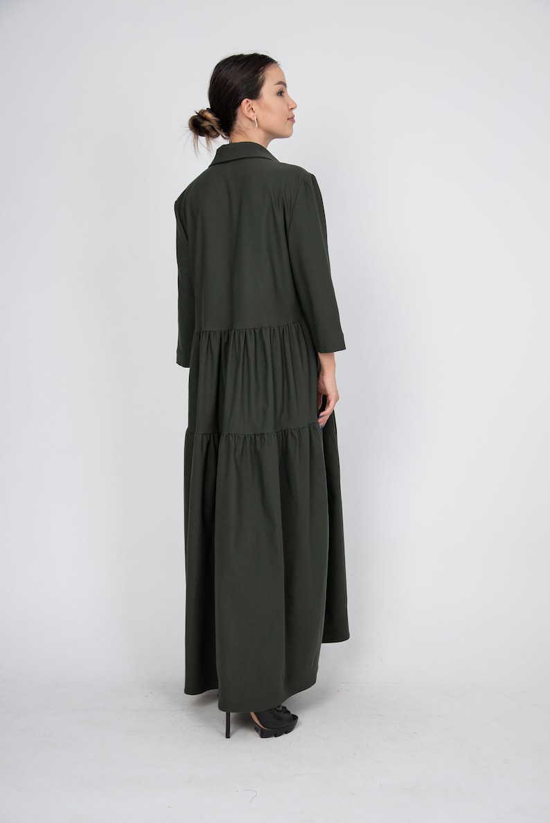 May include: A long, dark green tiered dress with a collared neckline and three-quarter sleeves.