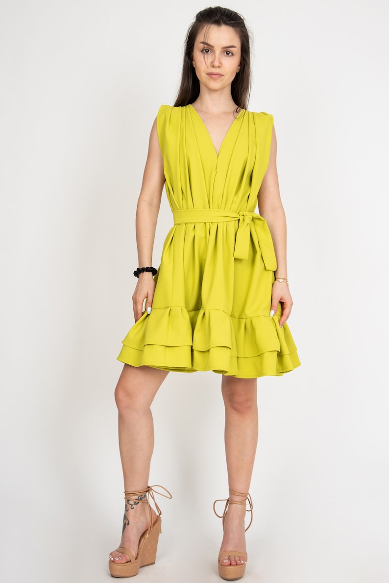 Peut inclure: Une robe sans manches vert citron avec un d&eacute;collet&eacute; en V, une ceinture &agrave; nouer &agrave; la taille et un ourlet &agrave; volants. La robe est faite d'un tissu l&eacute;ger et est parfaite pour l'&eacute;t&eacute;.