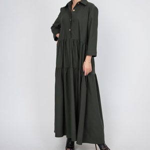 May include: A long-sleeved, dark green, button-down dress with a tiered skirt. The dress has a collared neckline and a relaxed fit.