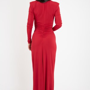 May include: A long-sleeved, red maxi dress with a fitted bodice and a gathered back. The dress has a V-neckline and a long, flowing skirt.