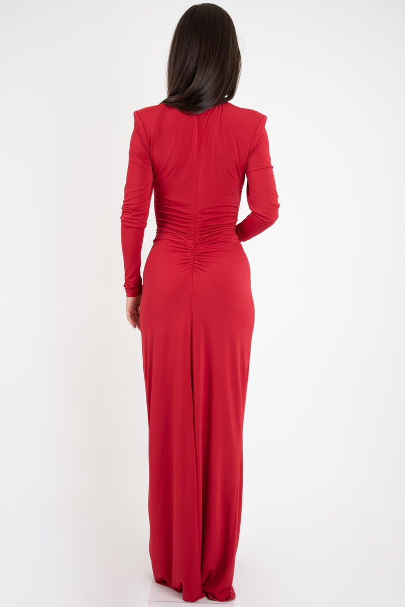 May include: A long-sleeved, red maxi dress with a fitted bodice and a gathered back. The dress has a V-neckline and a long, flowing skirt.