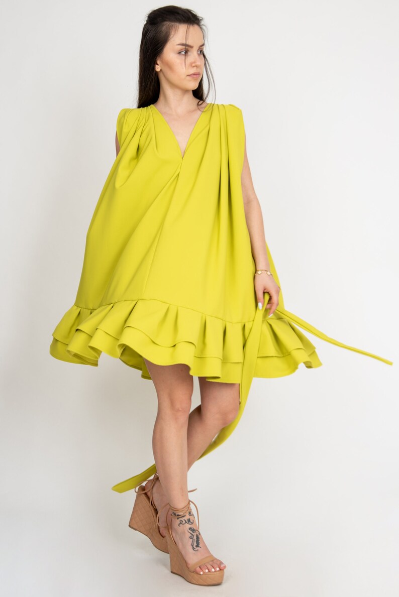 Peut inclure: Une robe sans manches vert citron avec un ourlet &agrave; volants et une ceinture &agrave; nouer &agrave; la taille. La robe est fluide et a une coupe ample.
