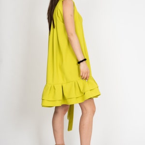 Peut inclure: Une robe sans manches vert citron avec un ourlet &agrave; volants. La robe a une ceinture &agrave; nouer &agrave; la taille et est port&eacute;e avec des sandales compens&eacute;es nudes.