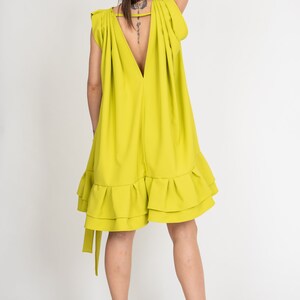 Peut inclure: Une robe sans manches vert citron avec un d&eacute;collet&eacute; en V profond et un ourlet &agrave; volants. La robe a une coupe ample et est faite d'un tissu l&eacute;ger.