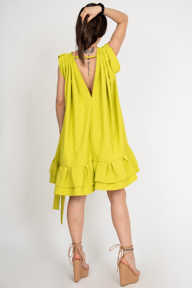 Peut inclure: Une robe sans manches vert citron avec un d&eacute;collet&eacute; en V profond et un ourlet &agrave; volants. La robe a une coupe ample et est faite d'un tissu l&eacute;ger.