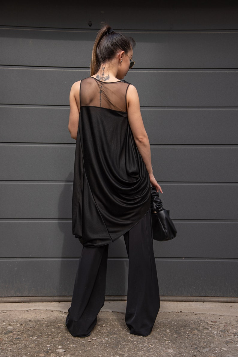 K&ouml;nnte beinhalten: Ein schwarzes &auml;rmelloses Oberteil mit einem durchsichtigen Mesh-R&uuml;ckenpanel und einem drapierten Design. Das Oberteil wird mit einer schwarzen weiten Hose kombiniert.