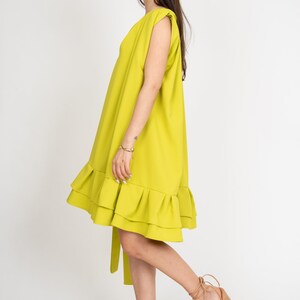 Peut inclure: Une robe sans manches vert citron avec un ourlet &agrave; volants et une ceinture &agrave; la taille. La robe est port&eacute;e par une personne aux cheveux longs bruns et est associ&eacute;e &agrave; des sandales compens&eacute;es beiges.