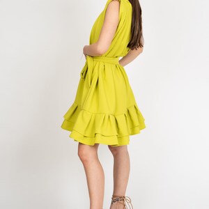 Peut inclure: Une robe sans manches vert citron avec un ourlet &agrave; volants et une ceinture &agrave; la taille. La robe est port&eacute;e avec des sandales compens&eacute;es beiges.