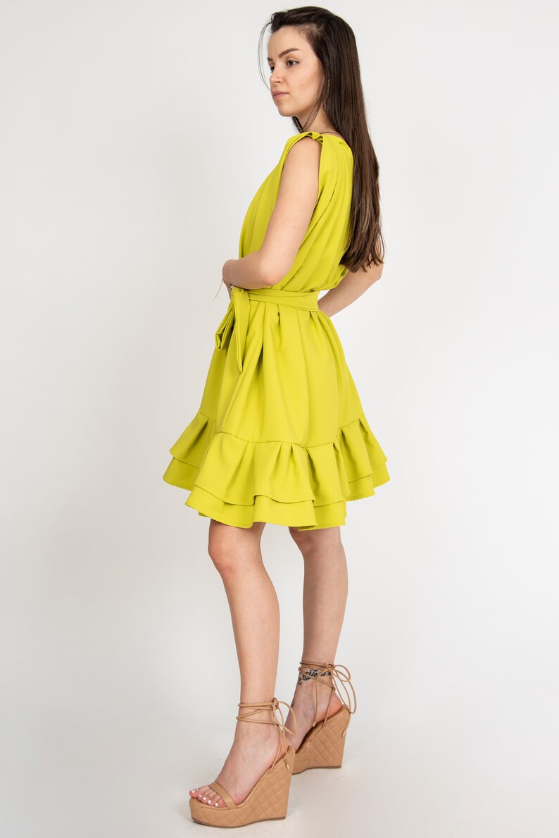 Peut inclure: Une robe sans manches vert citron avec un ourlet &agrave; volants et une ceinture &agrave; la taille. La robe est port&eacute;e avec des sandales compens&eacute;es beiges.