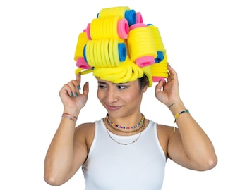 May include: A hair accessory constructed from numerous bright yellow foam rollers with blue and pink cylindrical centers, arranged in a dense, stacked formation to resemble a voluminous hairstyle, worn atop the head with a white tank top.