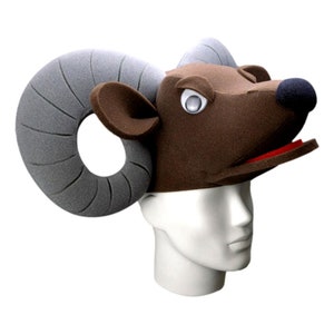 May include: A brown foam ram head costume with large gray foam horns. The costume has a red mouth and white eyes.
