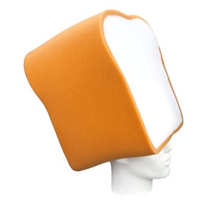 Può includere: Un cappello di pane in schiuma bianca con una crosta arancione. Il cappello è indossato su una testa di manichino bianca.