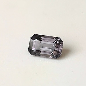 May include: A dark purple gemstone with a rectangular emerald cut.