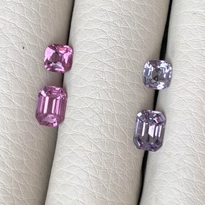 Pu&ograve; includere: Quattro pietre preziose sciolte, due rosa e due viola, sono esposte su una superficie bianca. Le pietre preziose sono tagliate in forma quadrata con bordi smussati.