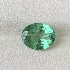 May include: A light green oval-shaped gemstone with facets.
