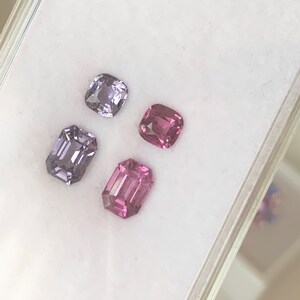 Pu&ograve; includere: Quattro pietre preziose sciolte in una scatola di esposizione bianca. Due sono di colore viola chiaro e due sono di colore rosa. Tutte e quattro le pietre preziose sono tagliate in forma rettangolare.
