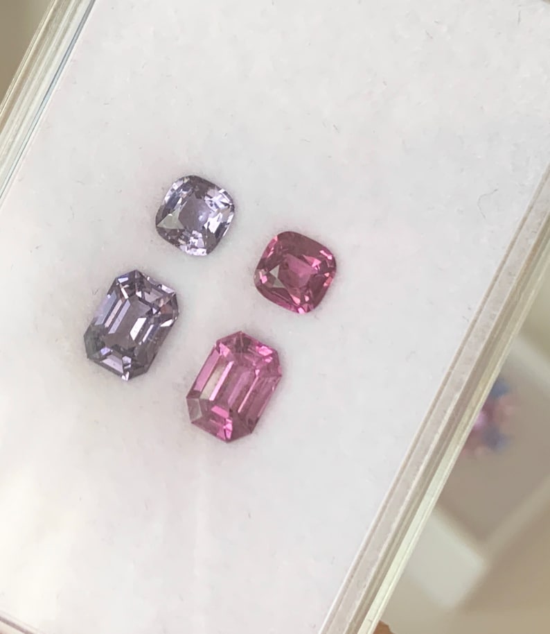 Pu&ograve; includere: Quattro pietre preziose sciolte in una scatola di esposizione bianca. Due sono di colore viola chiaro e due sono di colore rosa. Tutte e quattro le pietre preziose sono tagliate in forma rettangolare.