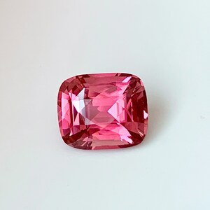 Puede incluir: Una piedra preciosa rosa con un corte de coj&iacute;n. La piedra est&aacute; facetada y tiene un alto pulido.