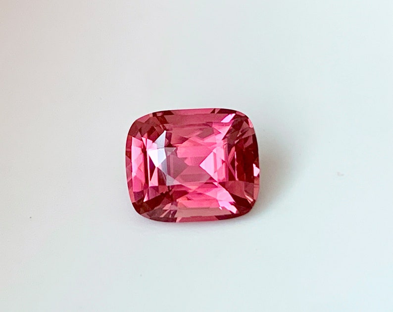 Puede incluir: Una piedra preciosa rosa con un corte de coj&iacute;n. La piedra est&aacute; facetada y tiene un alto pulido.