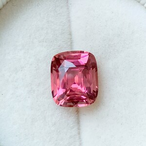 Puede incluir: Una piedra preciosa rosa con un corte de coj&iacute;n. La piedra preciosa est&aacute; engastada en un engaste blanco.