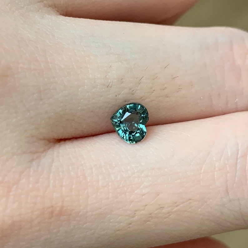 May include: A heart-shaped green gemstone with a faceted cut.
