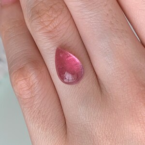 K&ouml;nnte beinhalten: Ein tropfenf&ouml;rmiger rosa Edelstein mit einer glatten, polierten Oberfl&auml;che.