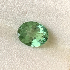May include: A light green oval-shaped gemstone with a star-like pattern inside.