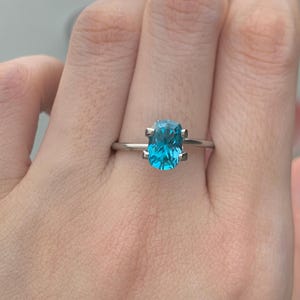 Puede incluir: Un anillo de plata con una piedra preciosa azul de talla coj&iacute;n.
