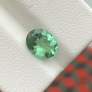 May include: A light green oval gemstone with a star-like pattern inside.
