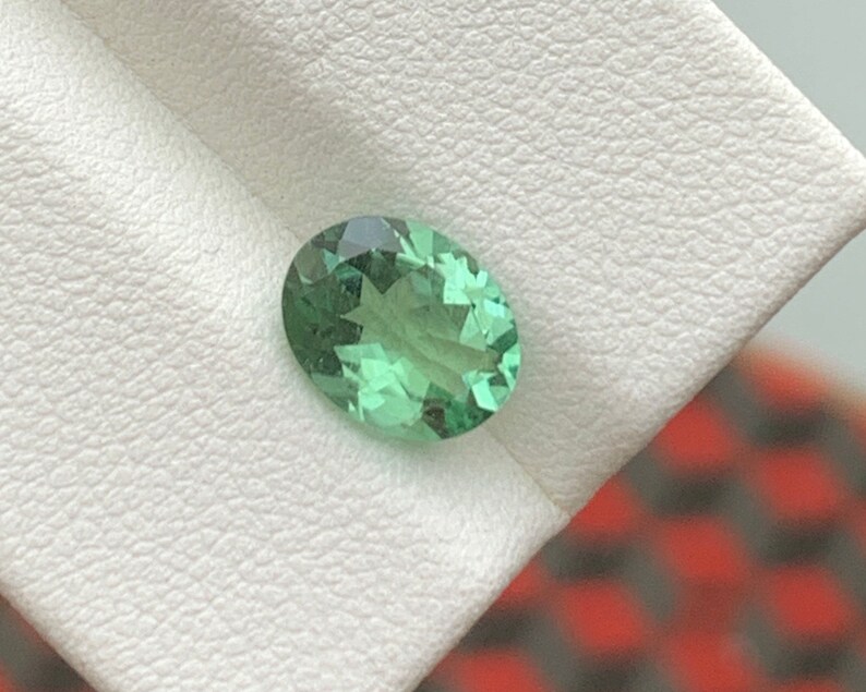 May include: A light green oval gemstone with a star-like pattern inside.