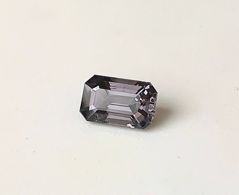 May include: A dark purple gemstone with a rectangular emerald cut.