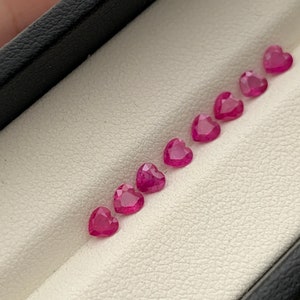 May include: A row of eight pink heart-shaped gemstones in a white velvet box.