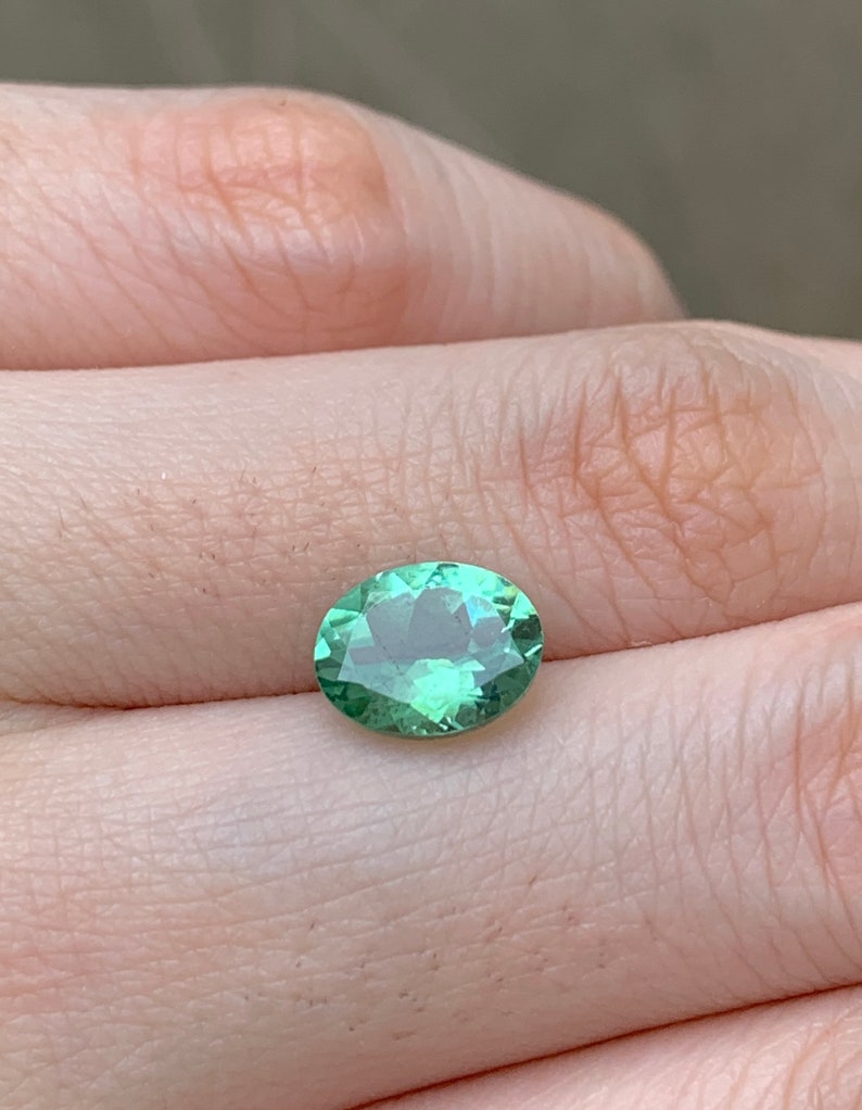 May include: A light green oval gemstone with a slight shimmer.