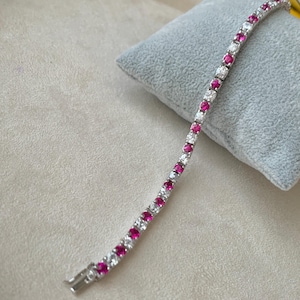 Op de afbeelding: Een zilveren tennisarmband met afwisselend roze en witte ronde stenen.