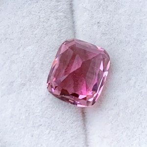 Puede incluir: Una piedra preciosa rosa con un corte de coj&iacute;n. La piedra est&aacute; facetada y tiene un acabado brillante.