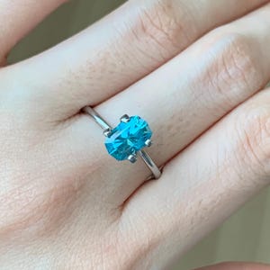 Puede incluir: Un anillo de plata con una gran piedra preciosa azul de forma ovalada.
