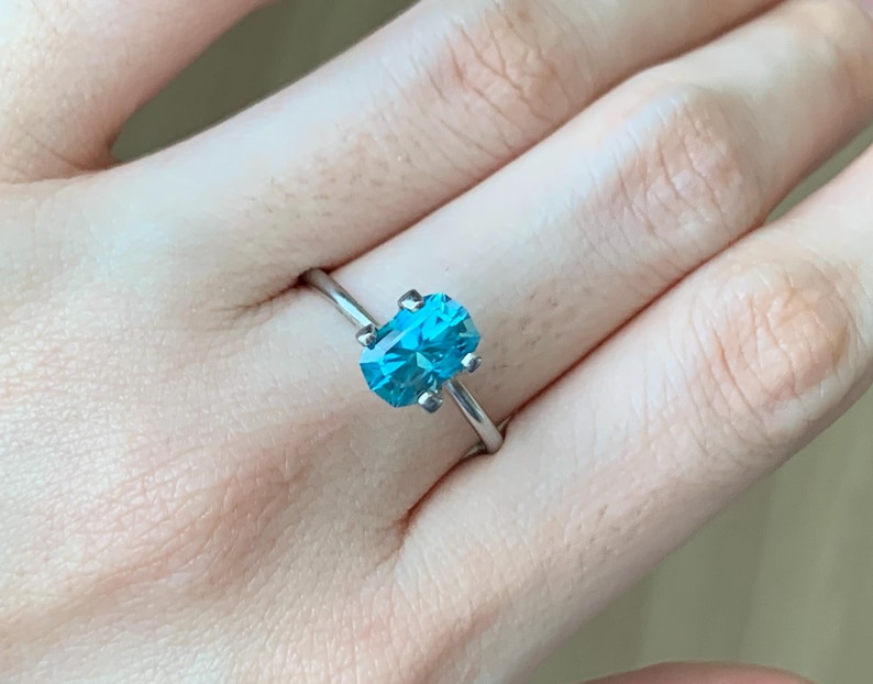Puede incluir: Un anillo de plata con una gran piedra preciosa azul de forma ovalada.