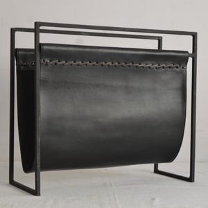 Puede incluir: Revistero de cuero negro con borde cosido, hecho de metal con acabado negro.