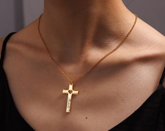 May include: A gold-colored cross pendant necklace. The cross has a heart-shaped cutout and the name "Michelle" engraved on it. The necklace is worn around the neck.