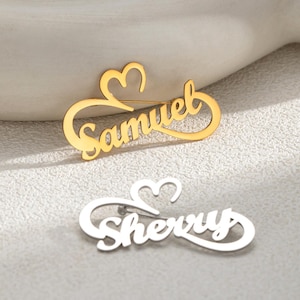 May include: Two personalised name brooches. One is gold-coloured with the name "Samuel" in a cursive font, and the other is silver-coloured with the name "Sherry". Each brooch features a heart design.