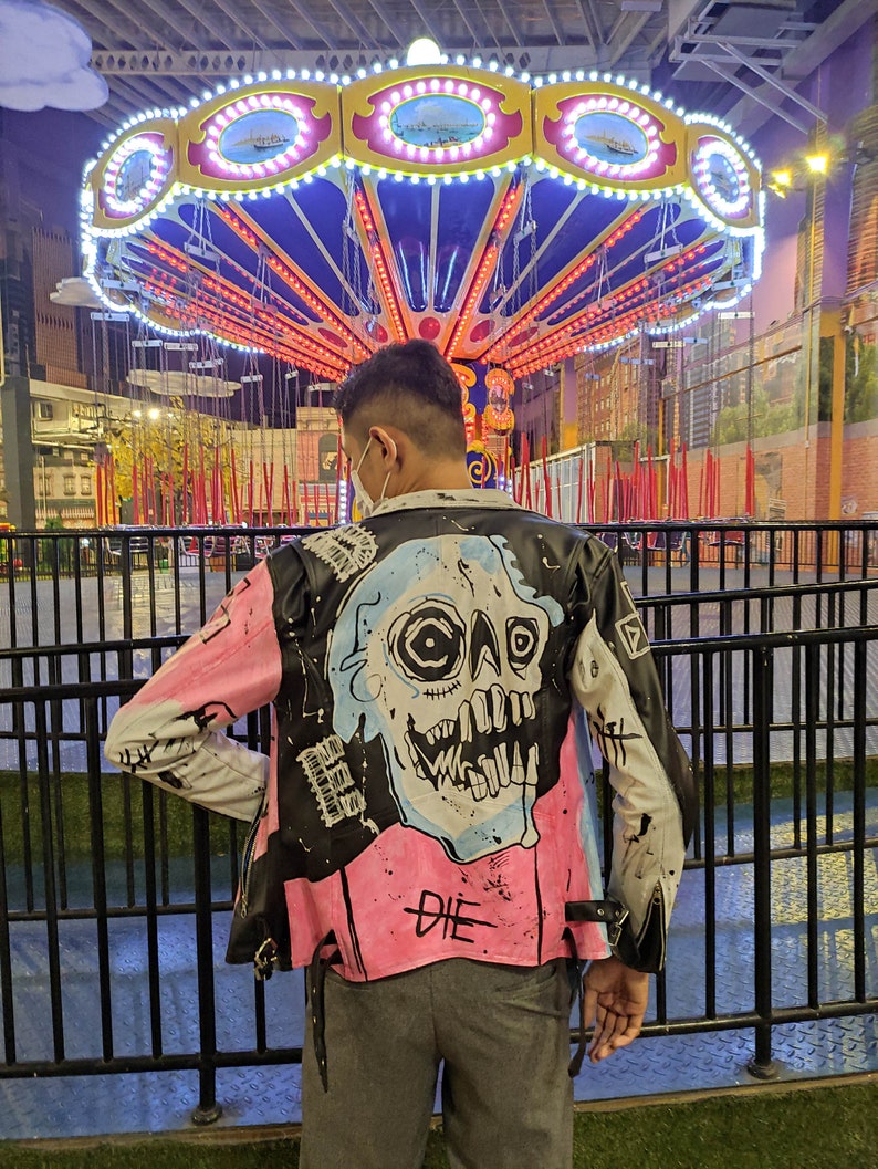 the appearance of a person wearing a painted jacket in front of a merry-go-round