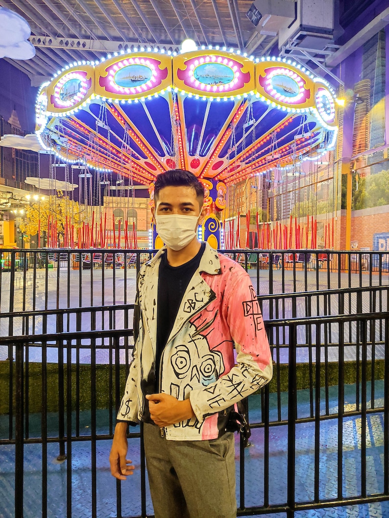 Model wearing a painted leather jacket designed by Lil Peep in front of the carousel