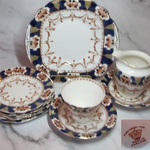 May include: A set of vintage Royal Crown China teacups and saucers with a blue and gold floral pattern. The set includes a teapot, creamer, and six teacups and saucers. The china is in excellent condition and has a beautiful, intricate design.